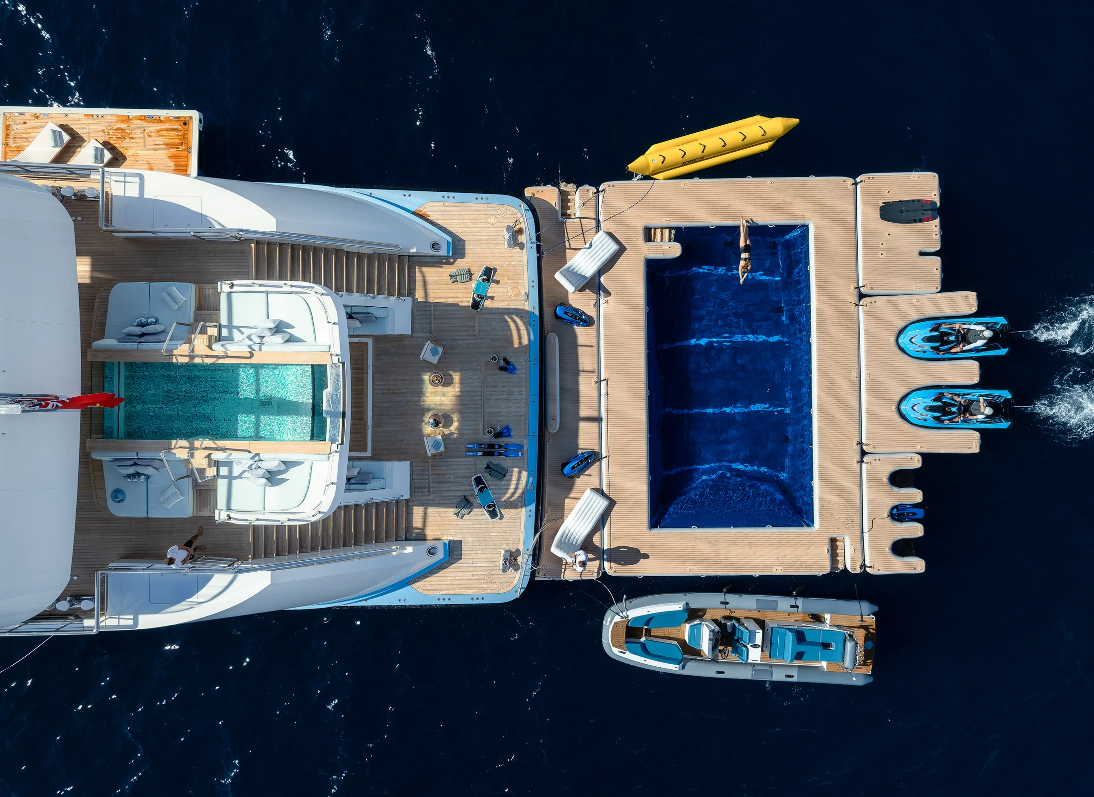 Aerial view of a superyacht’s stern with a floating pool, tender and water toys